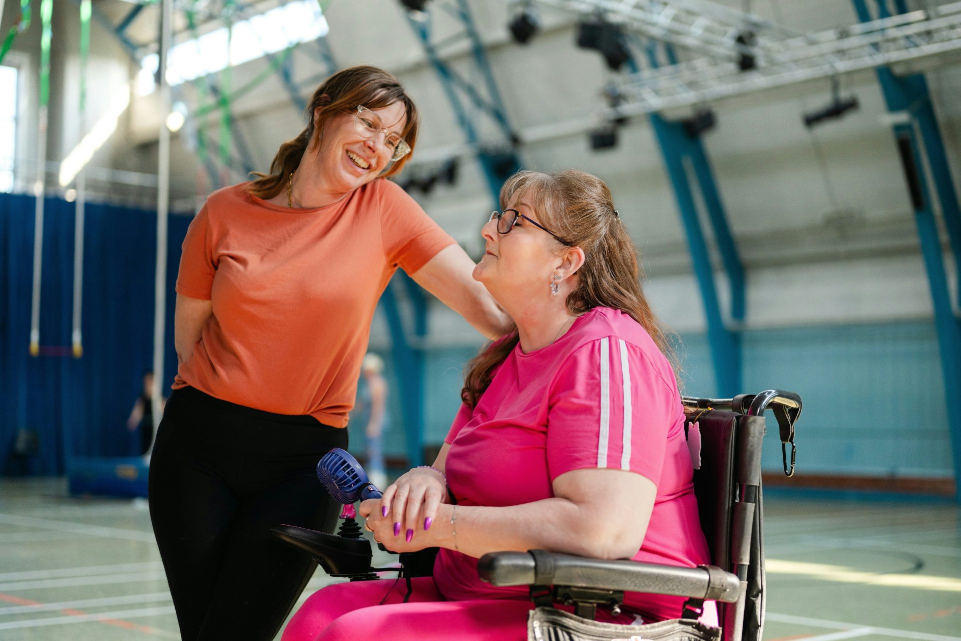 Zwei Frauen unterhalten sich in einer Turnhalle.
