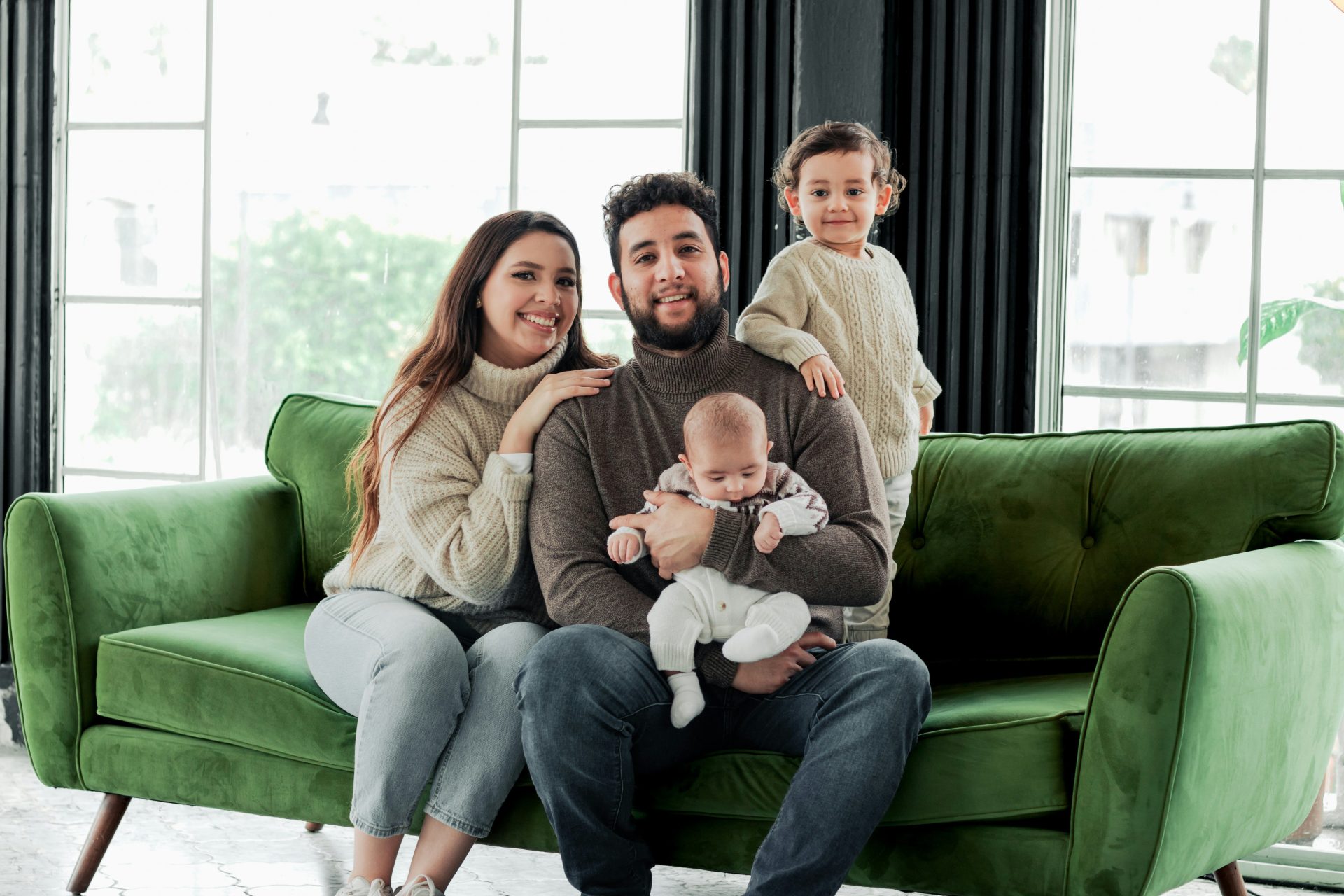 eine Familie, die auf einem grünen Sofa in einem Wohnzimmer sitzt